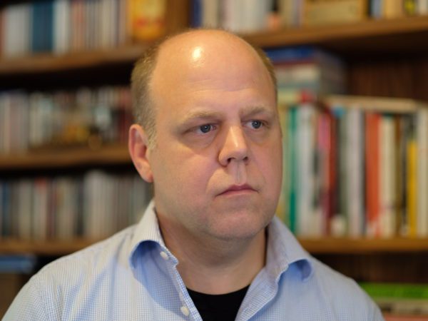 Man looking away from camera with books behind