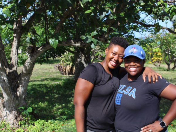 Two women dressed for fieldwork, smiling and hugging each other