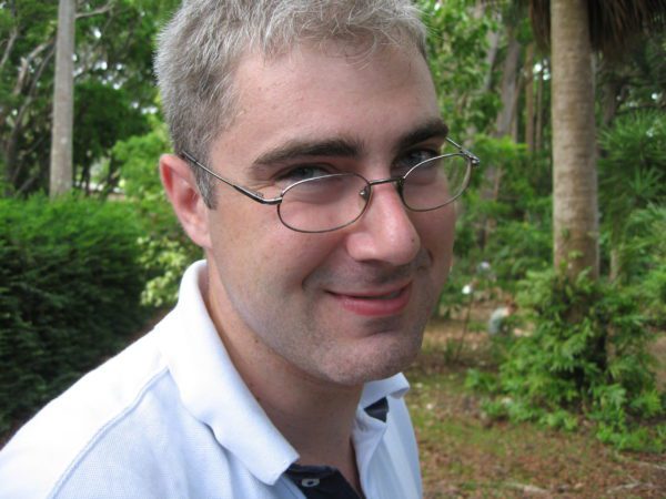 Man with white shirt, forest in background