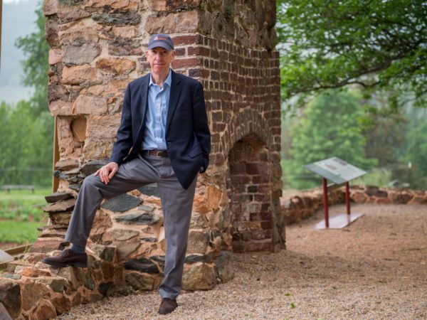 Fraser Neiman standing in front of a large chimney and remains of building on Monticello's Mulberry Row