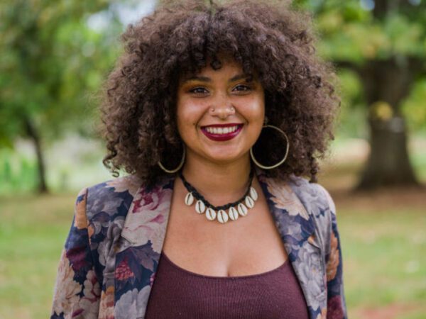 Woman with curly hair, posed with trees in background