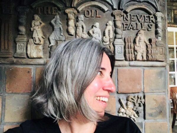 Woman in profile, smiling with a decorative frieze in background
