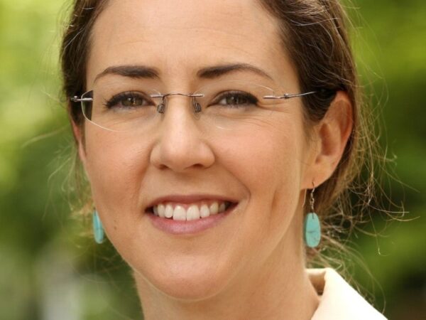 Close-cropped headshot of woman wearing glasses and turquoise earrings