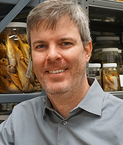 Man posed with jarred fish specimens behind him