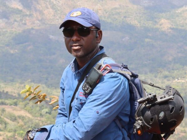 Man dressed for fieldwork with a mountain backdrop