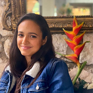 Woman wearing a denim jacket with a tropical plant in the background