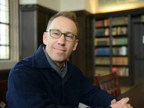 Man wearing glasses with bookshelf in background