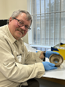 Man posed with an artifact in a lab