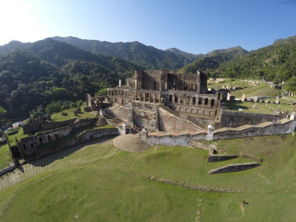 The ruins of a palace and terraced landscape with mountains and blue sky. Photo taken from above.